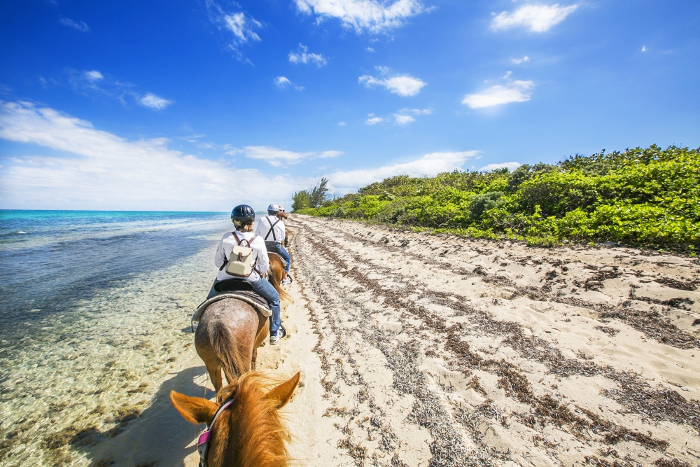 Jízda na koni na pláži u města Georgetown, Kajmanské ostrovy.
