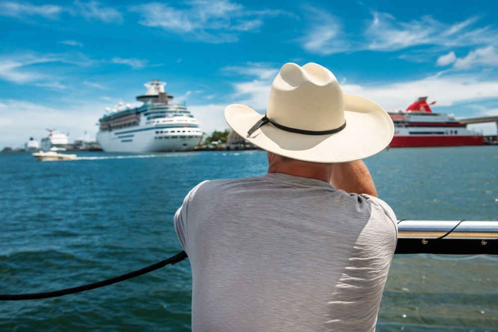 Muž v klobouku dívající se na zaoceánskou luxusní loď.